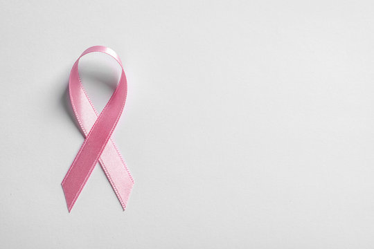 Pink ribbon on white background, top view. Cancer awareness