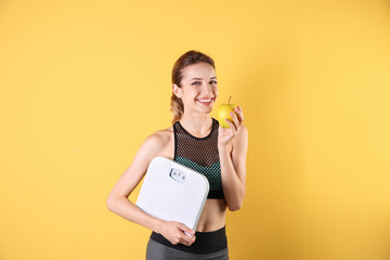 Young beautiful woman with scales and apple on color background. Weight loss motivation