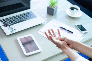 Business woman pressing the middle of her palm with her thumb to relieve pain due to a tendinitis...