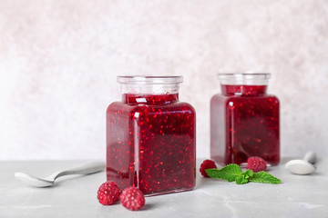 Jars with delicious raspberry jam on table