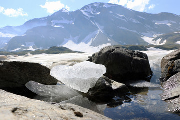 Piece of ice between stones in lake on Colle del Nivolet, Graian Alps, Italy, Piedmont, in...