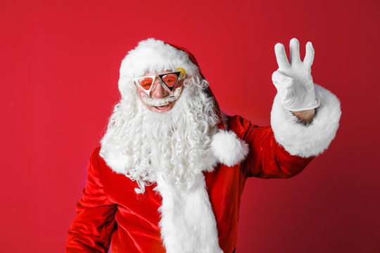 Authentic Santa Claus wearing sunglasses on color background