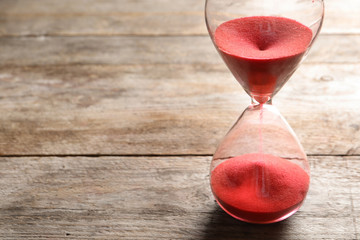 Hourglass with flowing sand on table. Time management