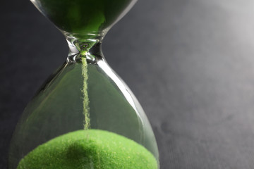 Hourglass with flowing sand on grey background, closeup. Time management
