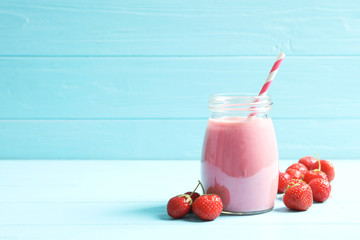 Glass jar with tasty strawberry smoothie on table