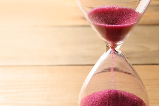 Hourglass with flowing sand on table, closeup. Time management