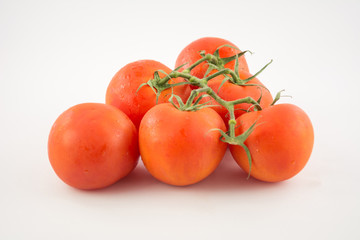 six unpeeled, fresh, red tomatoes with green tails on white background