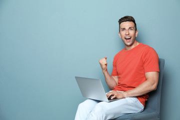 Man in casual clothes with laptop on color background
