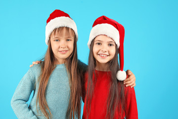 Cute little children in Santa hats on color background. Christmas celebration