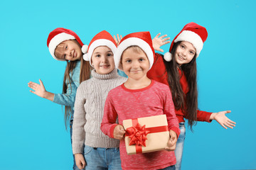 Cute little children in Santa hats on color background. Christmas celebration