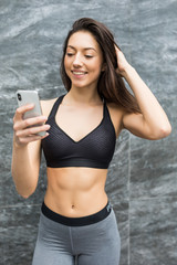 Fitness beauty woman in front of outdoors wall take selfie with smartphone in the city after workout to share in social networks