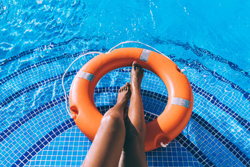 Woman legs in a swimming pool with lifesaver