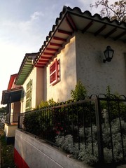 Casas colombianas tradicionales , muy coloridas, de estilo paisa, en Medellín, con pequeñas ventanas de colores típicos, lámpara exterior y jardín.