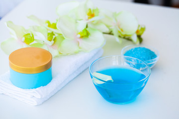 Organic Blue Sea Salt. Spa Composition With Cream, Salt, Towel and Flowers On a White Background. Wellness Products and Cosmetics.