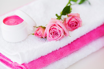 Obraz na płótnie Canvas Spa. Wellness Products and Cosmetics. Towels, cream and pink flowers for a spa relaxation on white background. Natural organic cosmetics for face care. Bath products, bathroom set