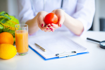 Diet. Doctor Nutritionist hold tomato in her office. Concept of natural food and healthy lifestyle....