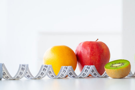 Diet. Fitness and healthy food diet concept. Balanced diet with fruit. Fresh fruit, measuring tape on white background. Closeup