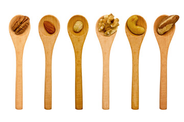 Various nuts in wooden spoons on white background