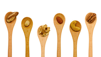 Various nuts in wooden spoons on white background