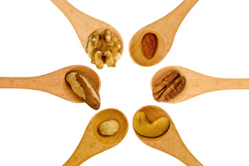 Various nuts in wooden spoons on white background