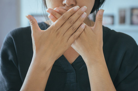 Asian woman covering her mouth and smell her breath with hands upter wake up,Bad smell