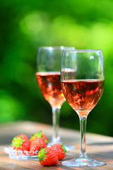 Two glasses Rose Wine and fresh strawberries, defocused deep green and bright outdoor background 3