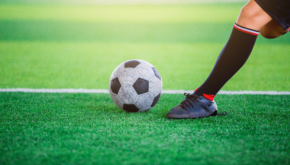 The soccer player shoot ball on artificial turf.