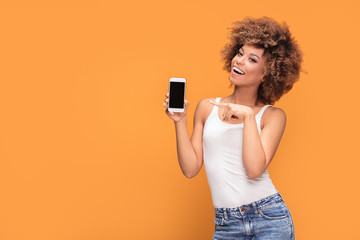 Smiling afro girl showing blank screen mobile phone.