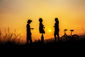 Fototapeta na wymiar Silhouette group of happy children playing on mountain at sunset, summer time