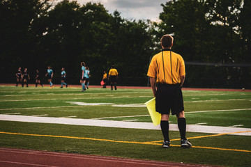 Soccer referee wearing yellow at youth girls soccer game at sunset