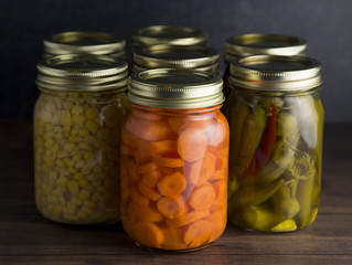 Various Types of Canned Vegetables on a Wooden Table in a Dark Environment