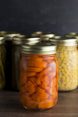 Various Types of Canned Vegetables on a Wooden Table in a Dark Environment