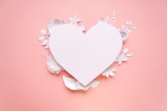 White paper flowers, lined in the shape of a heart on pink background. Cut from paper.