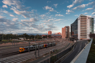 Fototapeta premium Train leaves the city of Adelaide as the sun sets