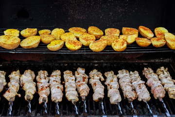 Skewers made from potatoes and meat as well as kebabs on the grill outdoors