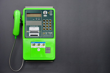 green public telephone on black background, copy space