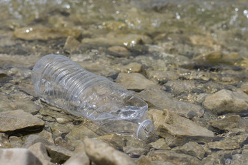 Empty water bottle littering lake shore