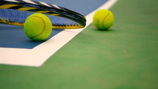 Close up of tennis equipment on the court. Sport, recreation concept. Yellow racket with a tennis ball in motion on a clay green blue court next to the white line with copy space and soft focus.