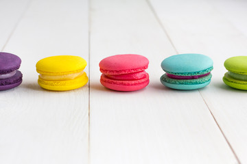 Colorful Macaroons on white wooden background.