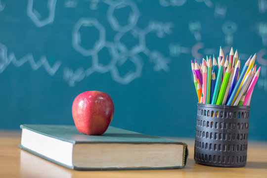Composition of stationery ,books and an red apple on the desk,The background is blackboard, educational concepts