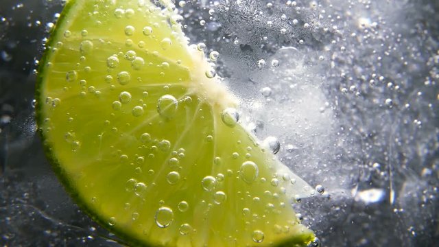Macro close-up,refreshing soda tonic fizzy water, lime in Glass, ice. Slice of lemon, mineral bubbles. Detox or thirst concept. Healthy, dietary nutrition. Cold lemonade mojito drink. Black background