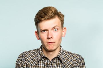puzzled confused bewildered shocked amazed man. comical reaction. portrait of a young guy on light background. emotion facial expression and feelings concept.