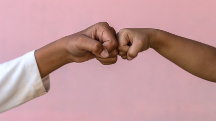 Both hands fist against the pink wall.