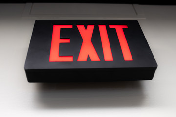 Black exit sign with red letters hanging on the wall