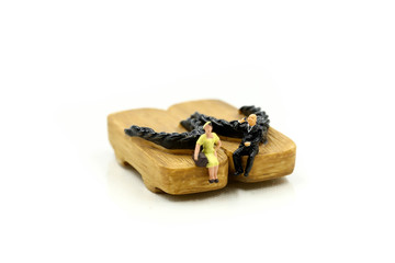 Miniature people : couple people sitting on Japanese wooden shoes (geta)