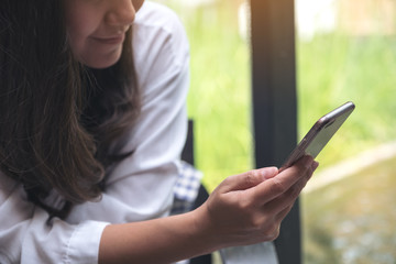 Closeup image of an asian woman holding , using and looking at smart phone