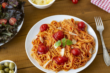 spaghetti with tomato sauce in the dish on the wooden table