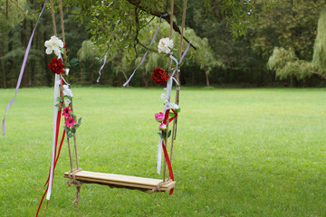Swing, decorated with flowers hanging in the park in summer