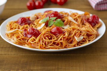 spaghetti with tomato sauce in the dish on the wooden table