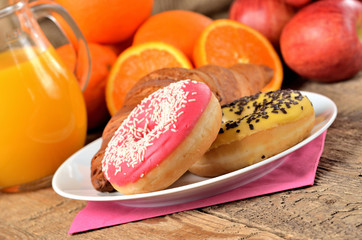 Detail of donuts, orange juice, croissant - sweet breakfast on wooden table